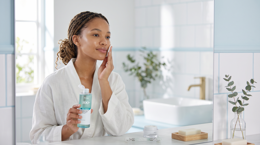 Young South African woman applying toner during her morning K-beauty routine in a soft blue bathroom